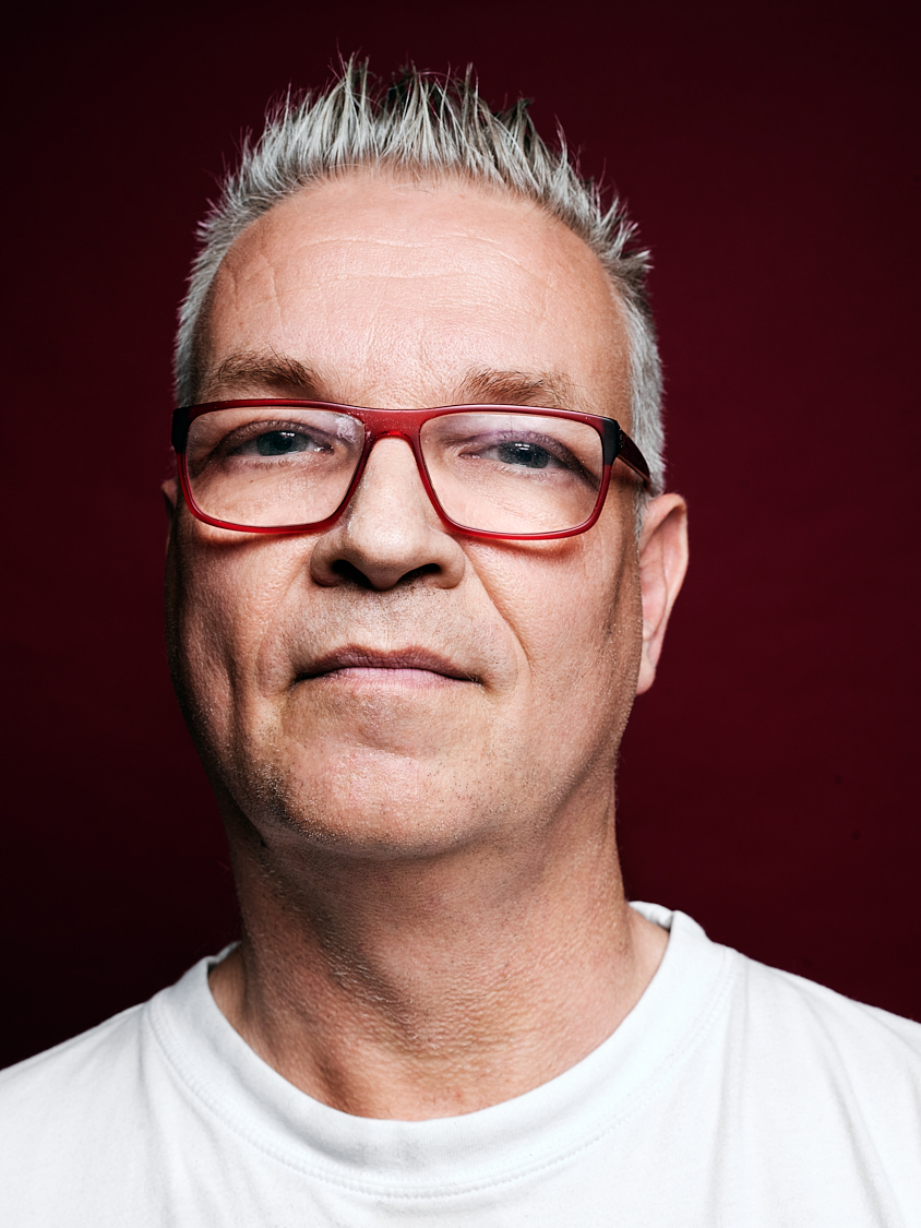 Man mit Brille vor Hintergrund Studio